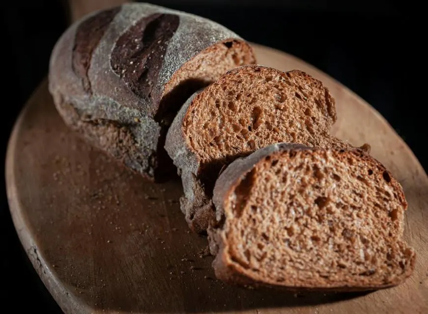 Slices of Brown Bread with scattered rye grains on a wooden board.