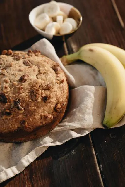 Banana bread and fresh bananas on a white cloth on table.