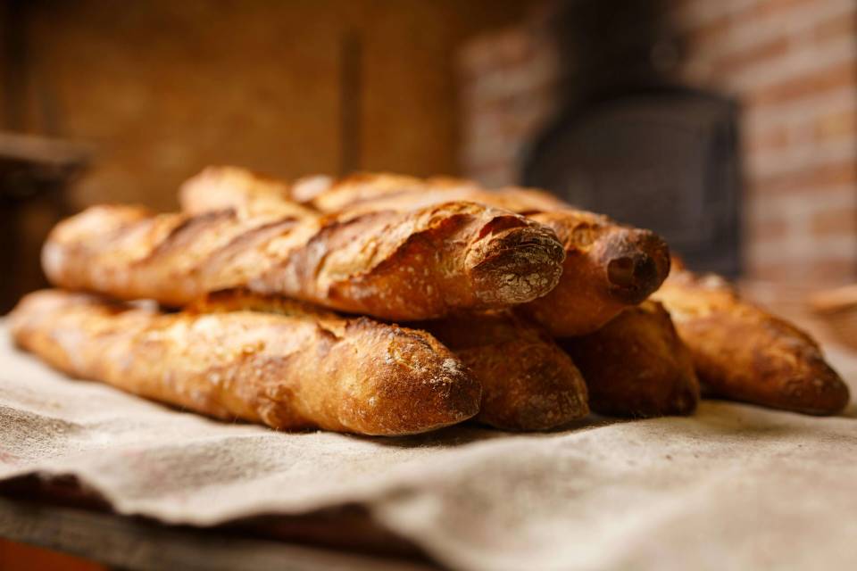 A pile of french breads on a white cloth on wooden table.
