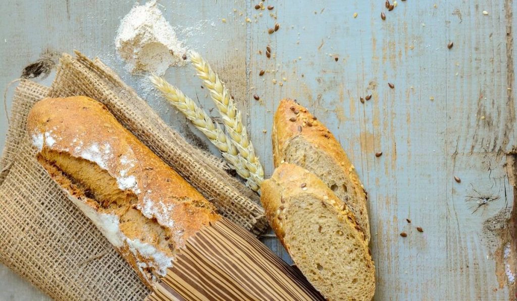 French bread in a paper with two pieces beside it.