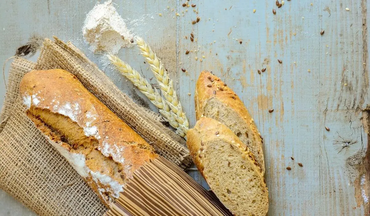 French bread in a paper with two pieces beside it.