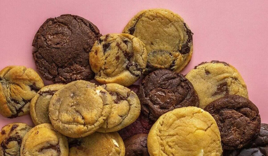 A bunch of chocolate chip cookies with pink background.