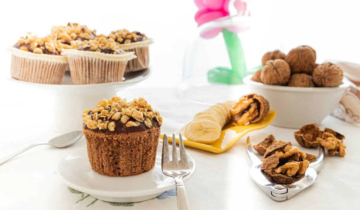 Sourdough Banana muffins on white ceramic plate with sliced banana and walnuts decoration