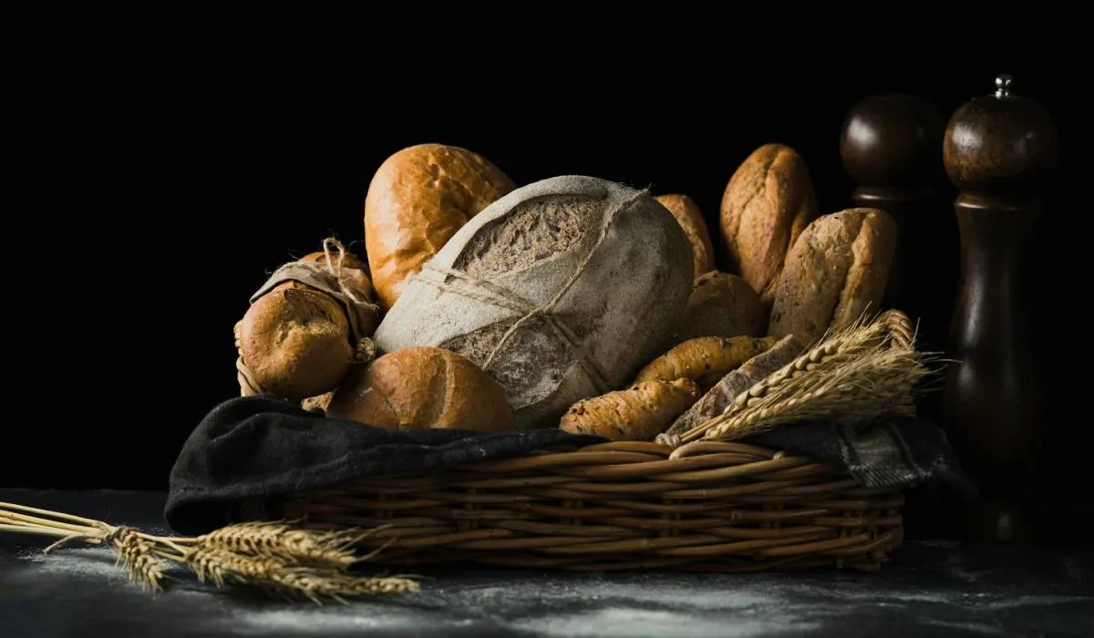 Different types of bread in a basket on a table.