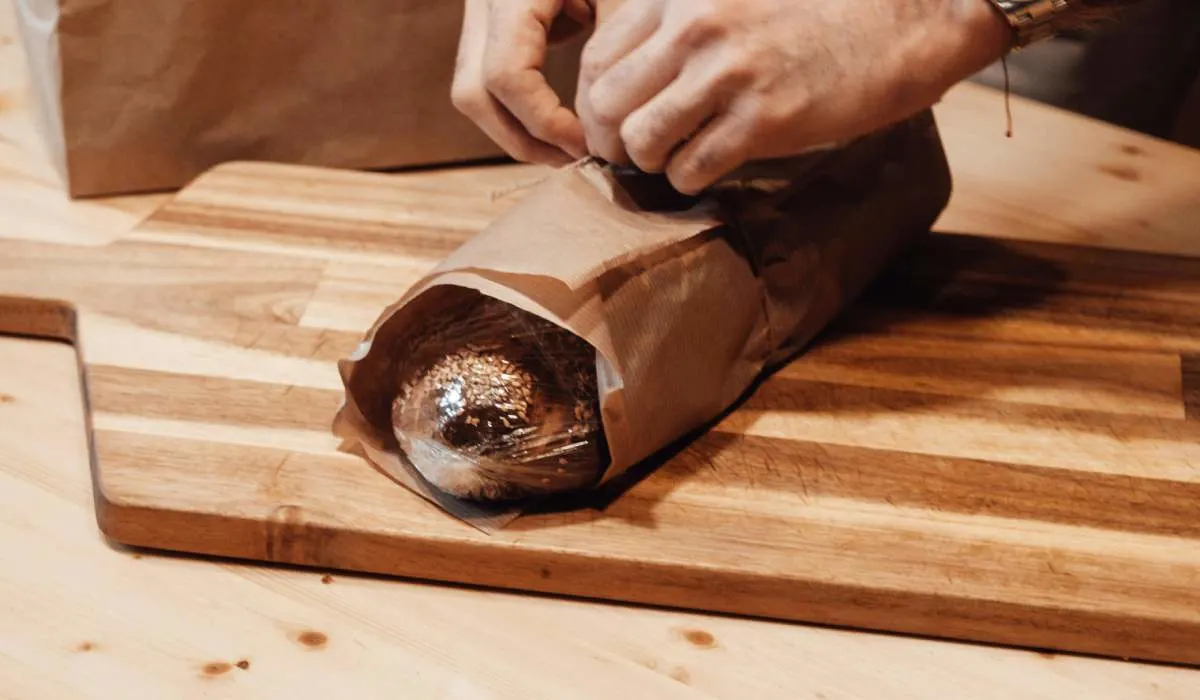 Person packing up bread on a wooden plate