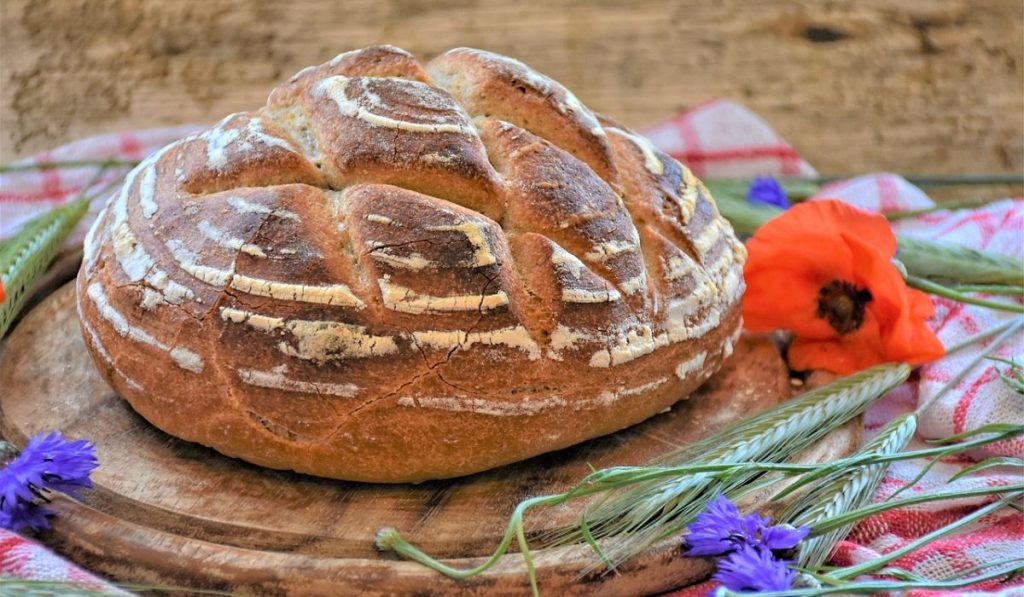 Sourdough bread on a wooden plate with flowers around