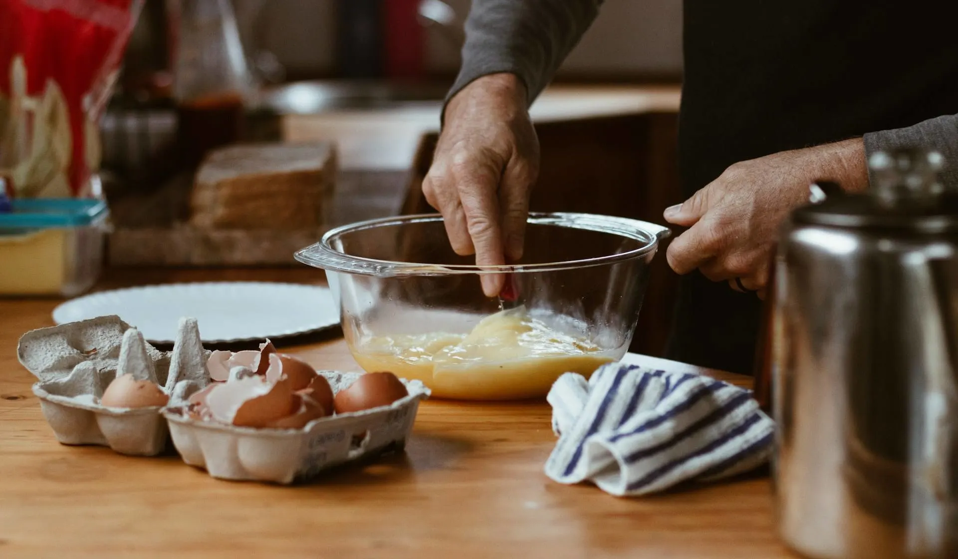 A man stirring eggs in a glass bowl