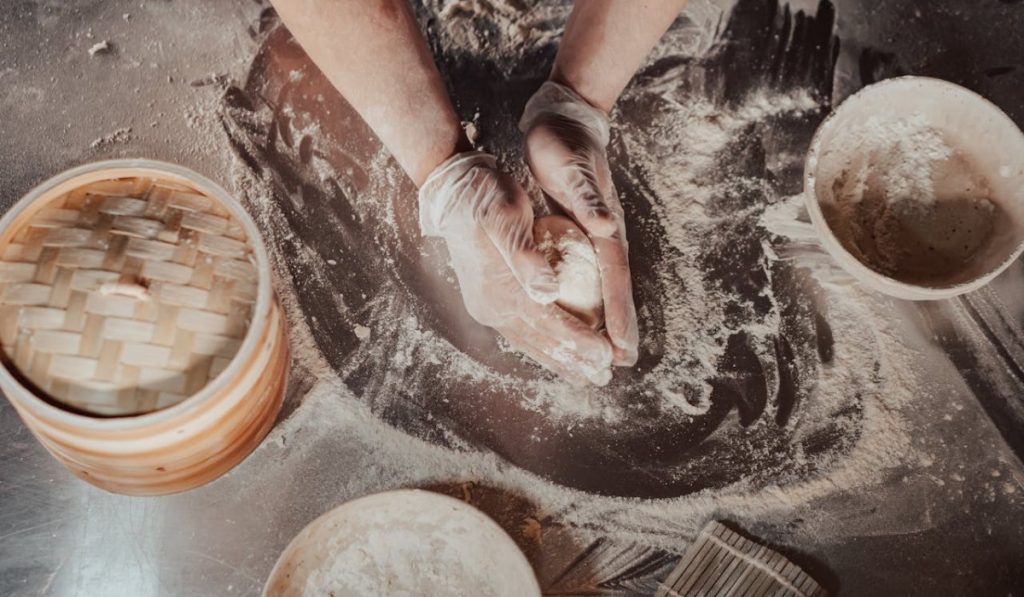 A person kneading dough before checking up the windowpane test