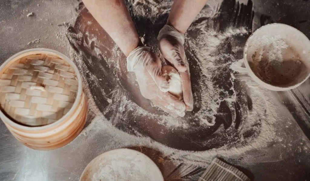 A person kneading dough before checking up the windowpane test