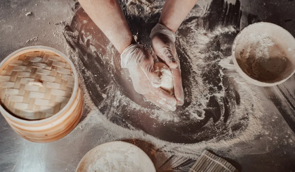 A person kneading dough before checking up the windowpane test