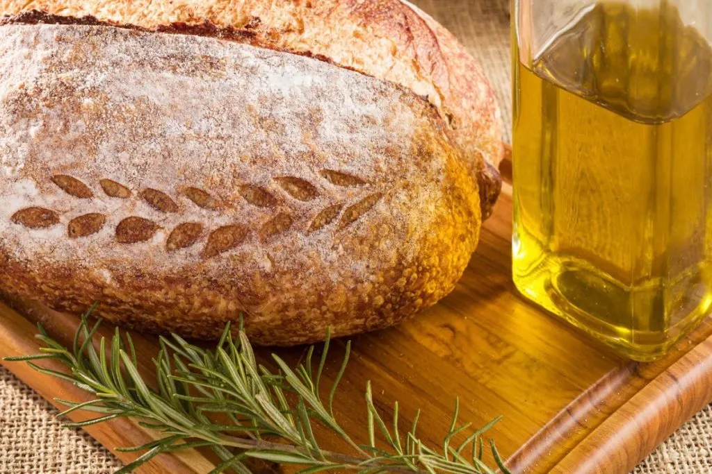Sourdough Olive and Rosemary bread on a wooden plate with olive oil