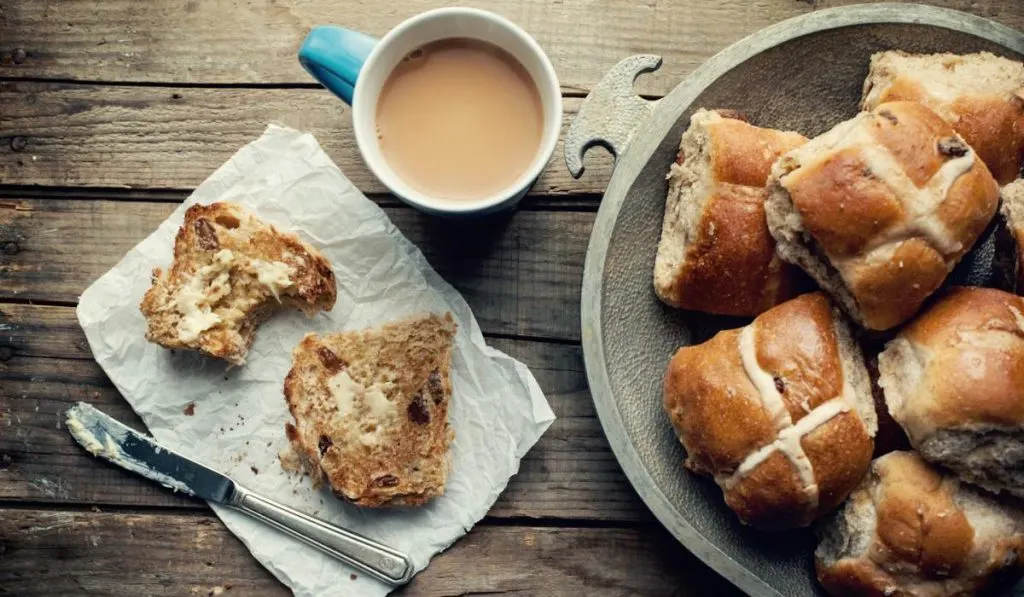 A breakfast with hot cross buns and a glass of milk