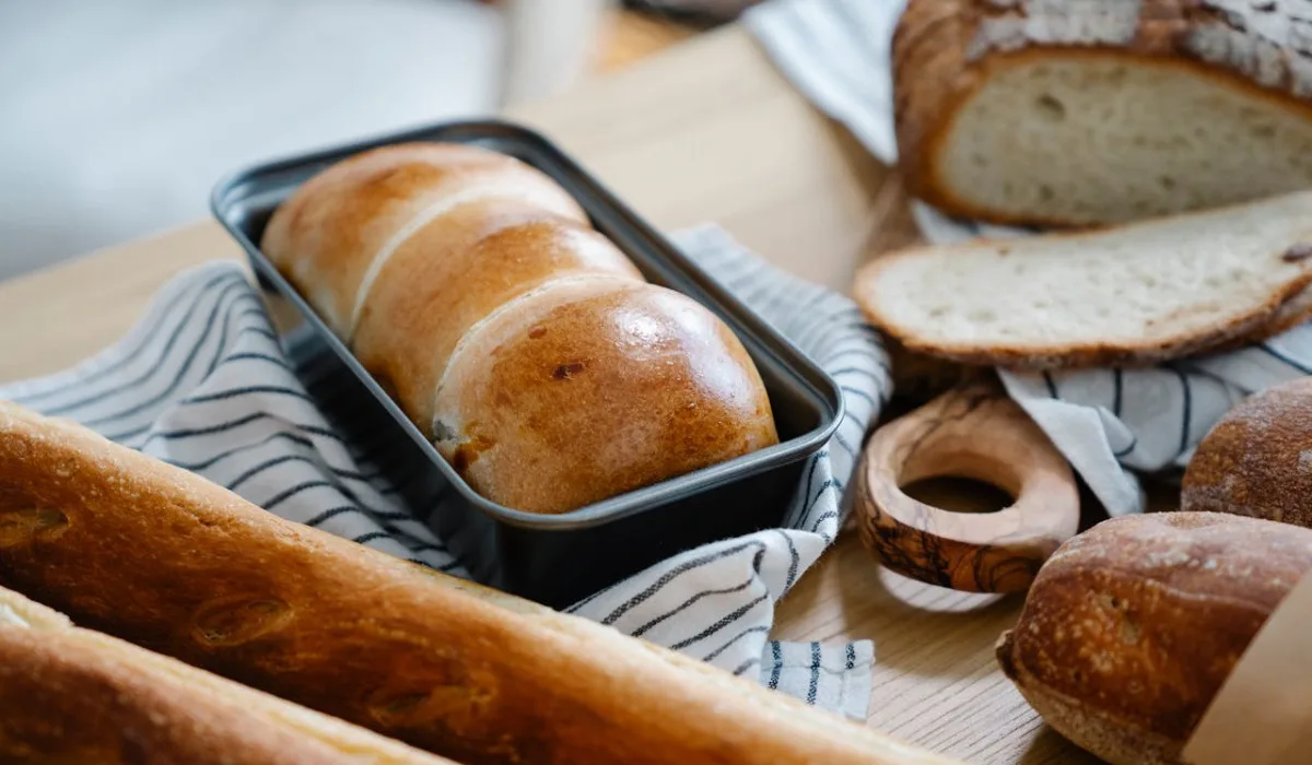 Loaf in a pan with breads on a wooden table
